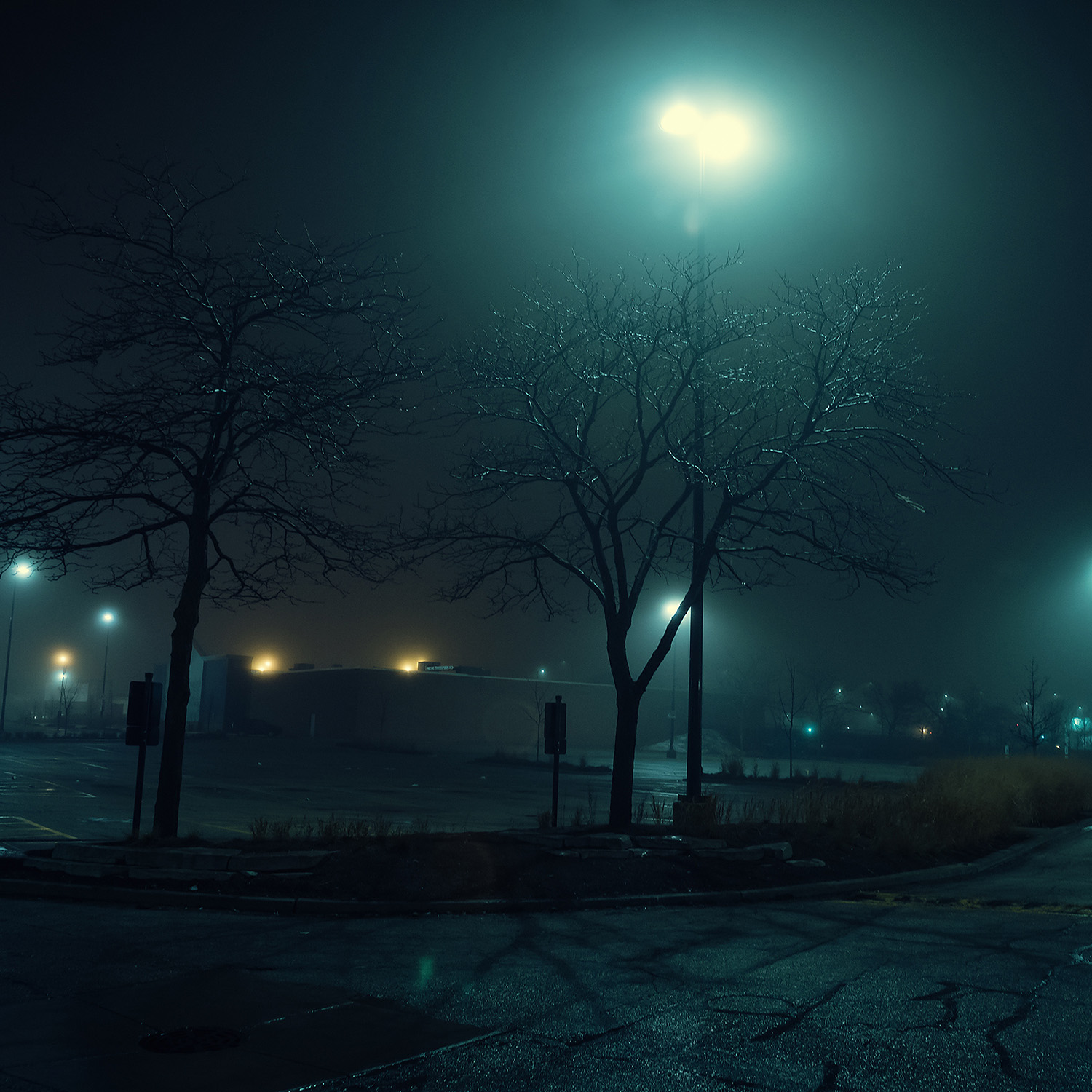 An eerie and foggy city night by a large empty urban shopping ma